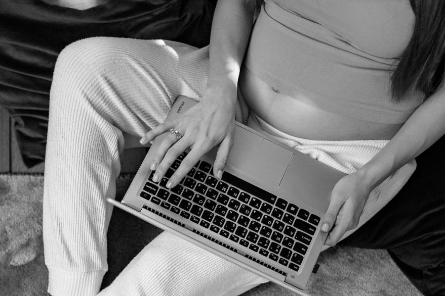 Bildnachweis: pexels-yankrukov-7156521 Eine schwangere Frau sitzt an einem Laptop.